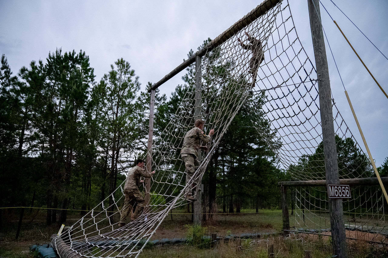 soldiers climbing a net obstacle at ranger school